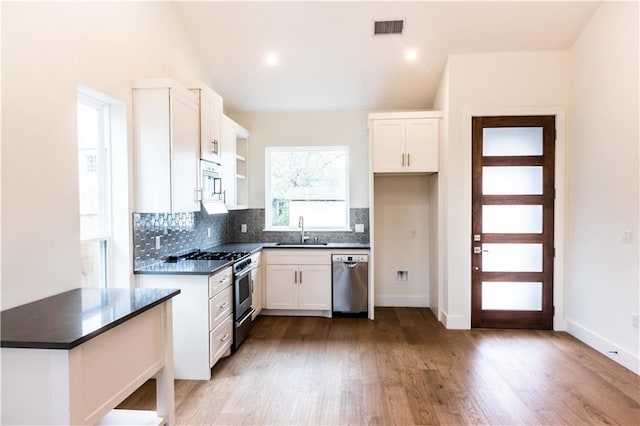 409 W 35th St Unit B, Austin, TX 78705 - kitchen with stainless steel appliances, a sink, dark countertops, decorative backsplash, and white cabinetry