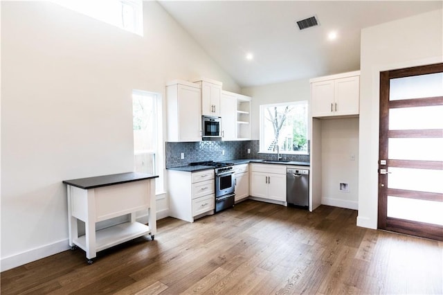 kitchen with visible vents, open shelves, a sink, stainless steel appliances, and dark countertops