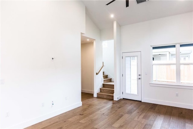 foyer featuring stairway, baseboards, a ceiling fan, and light wood finished floors