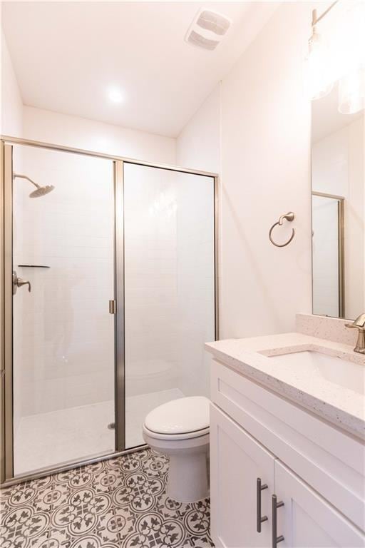 full bathroom featuring vanity, toilet, visible vents, and a stall shower