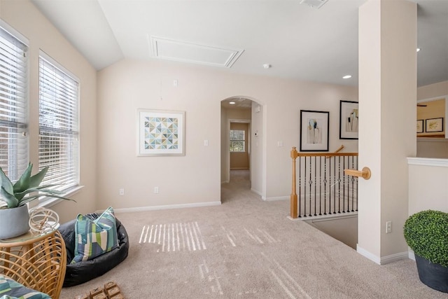 living area featuring vaulted ceiling, carpet flooring, baseboards, and arched walkways