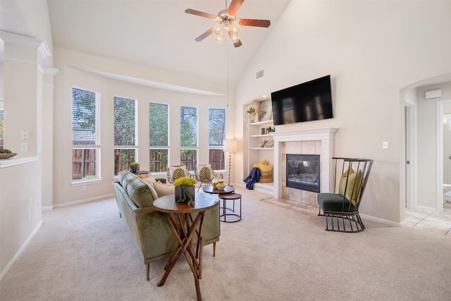 living room featuring built in shelves, carpet, high vaulted ceiling, a fireplace, and ceiling fan