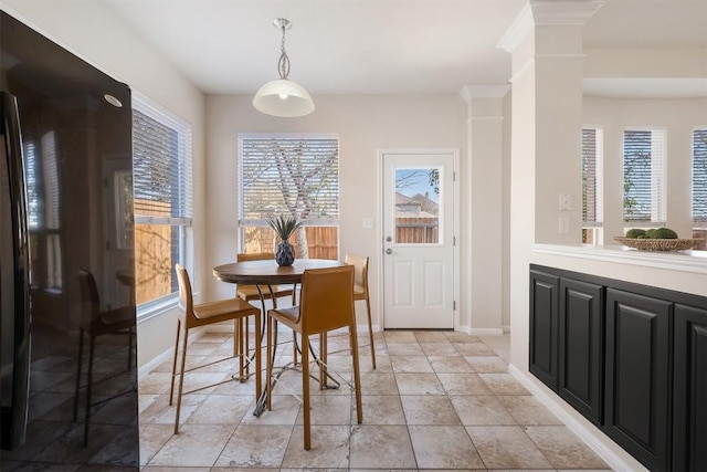 dining area with baseboards and ornate columns