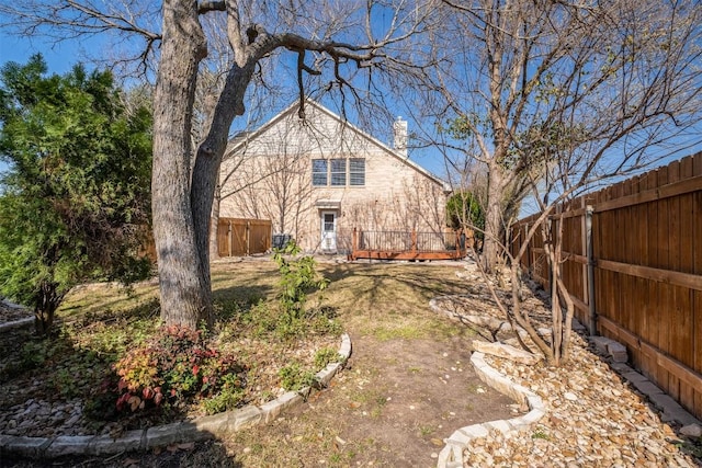 back of property with a fenced backyard and a chimney