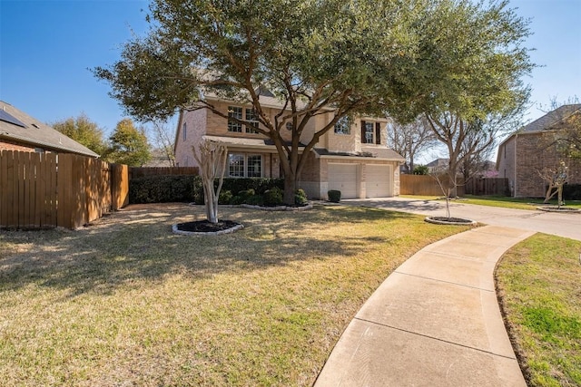 traditional home with a front lawn, concrete driveway, an attached garage, and fence