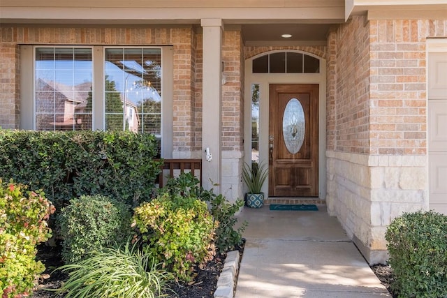 property entrance featuring a garage and brick siding