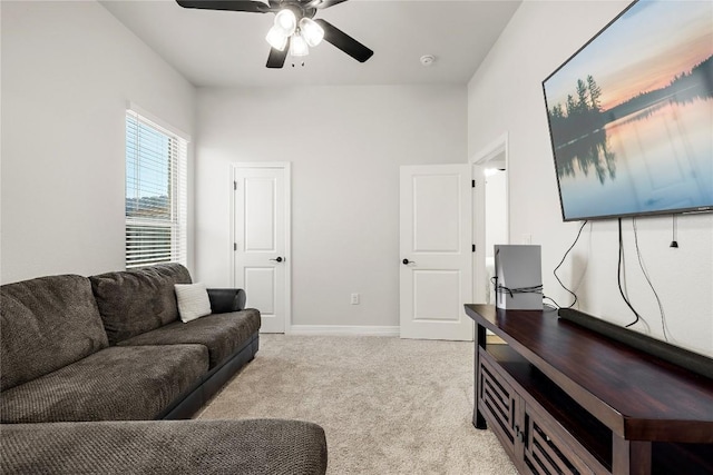 living room featuring baseboards, light carpet, and ceiling fan