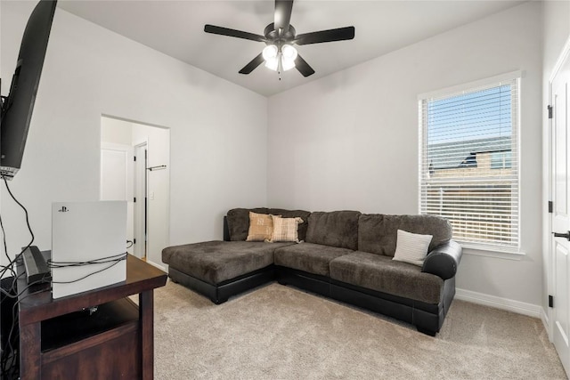 living area featuring baseboards, light colored carpet, and ceiling fan