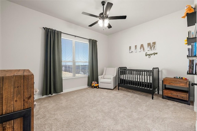 carpeted bedroom featuring baseboards, a nursery area, and a ceiling fan