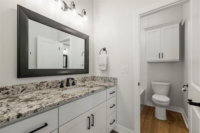 full bath with toilet, vanity, baseboards, and wood finished floors