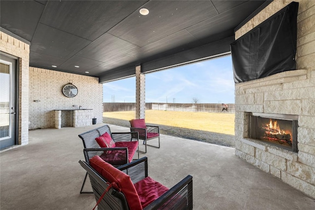 view of patio featuring fence and an outdoor stone fireplace