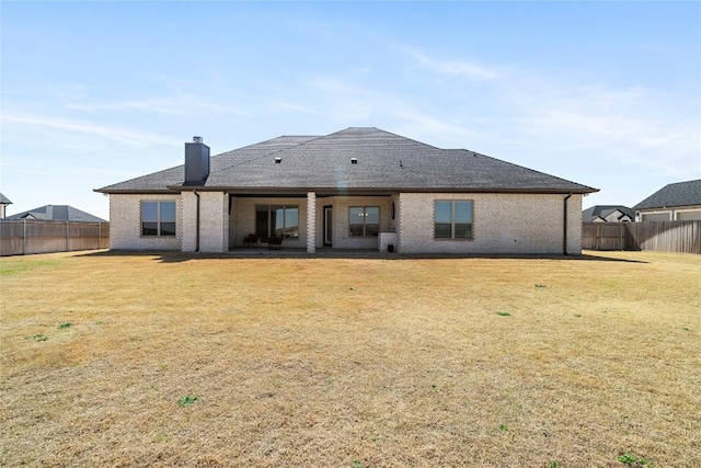 back of house with brick siding, a lawn, a patio, and a fenced backyard