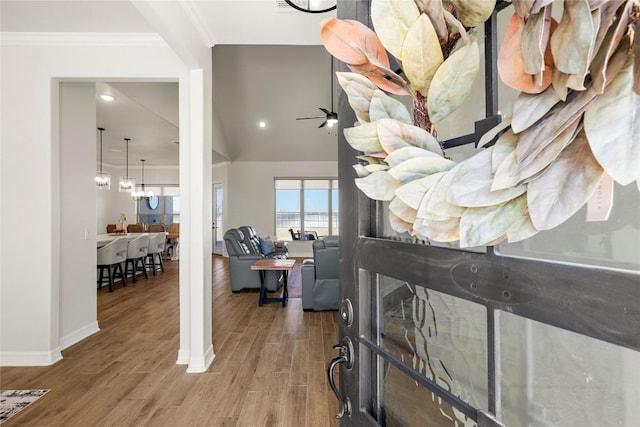 foyer featuring ornamental molding, ceiling fan with notable chandelier, baseboards, and wood finished floors