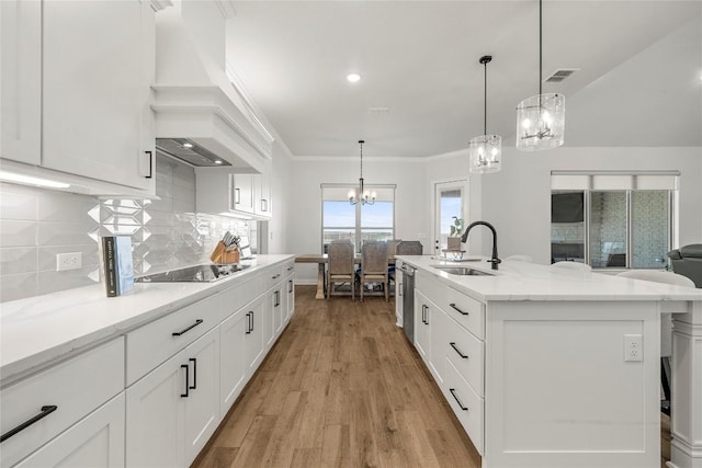 kitchen with backsplash, premium range hood, a chandelier, black electric cooktop, and a sink