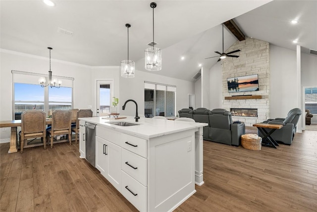 kitchen with wood finished floors, beamed ceiling, a fireplace, and a sink