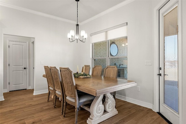 dining area with wood finished floors, baseboards, ornamental molding, a brick fireplace, and a notable chandelier