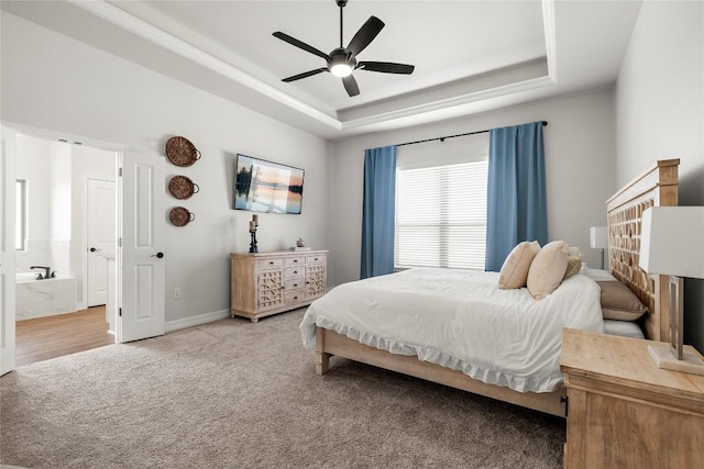 bedroom featuring baseboards, ceiling fan, light carpet, a raised ceiling, and connected bathroom