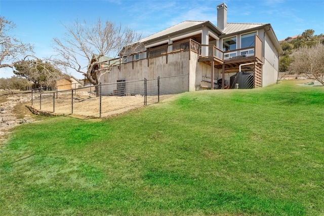 back of house with a chimney, metal roof, a yard, and fence