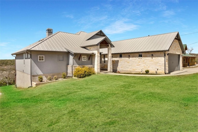 view of front of house featuring a front yard, a standing seam roof, a garage, stone siding, and metal roof