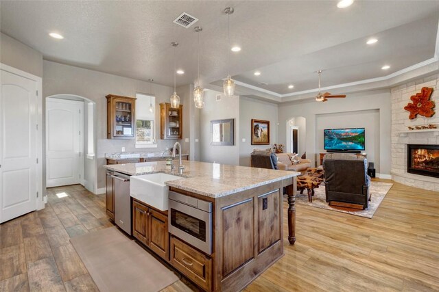 kitchen featuring a sink, brown cabinets, arched walkways, and stainless steel appliances