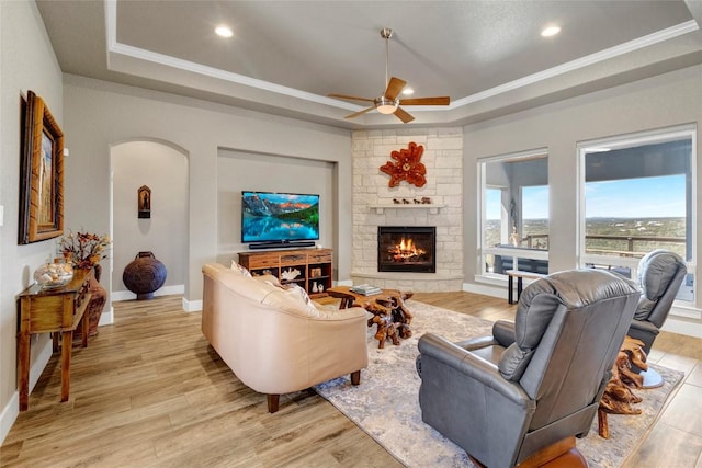 living room featuring a raised ceiling, recessed lighting, light wood-style floors, crown molding, and baseboards