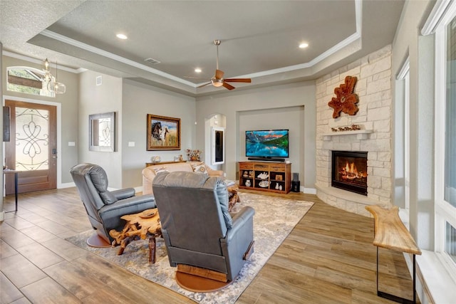 living room featuring visible vents, a tray ceiling, ornamental molding, a fireplace, and wood finished floors