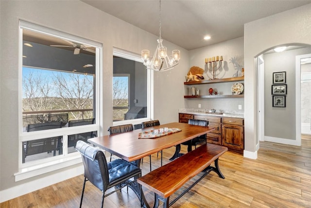 dining space with recessed lighting, light wood-type flooring, arched walkways, and baseboards