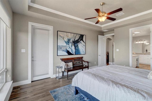 bedroom featuring a raised ceiling, light wood-style floors, arched walkways, and baseboards