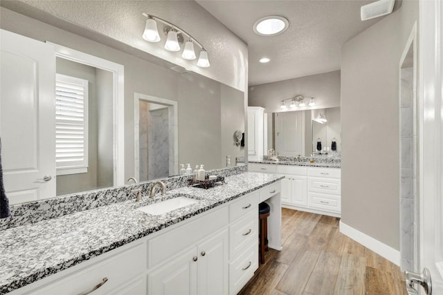 bathroom with visible vents, baseboards, vanity, wood finished floors, and a textured ceiling