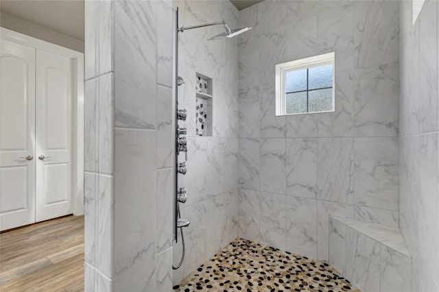 bathroom with a marble finish shower and wood finished floors