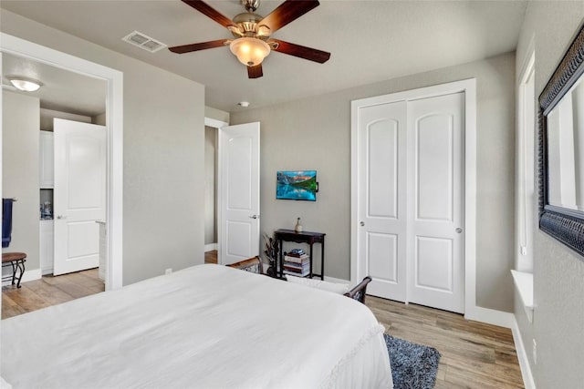 bedroom with light wood-type flooring, visible vents, baseboards, and a closet