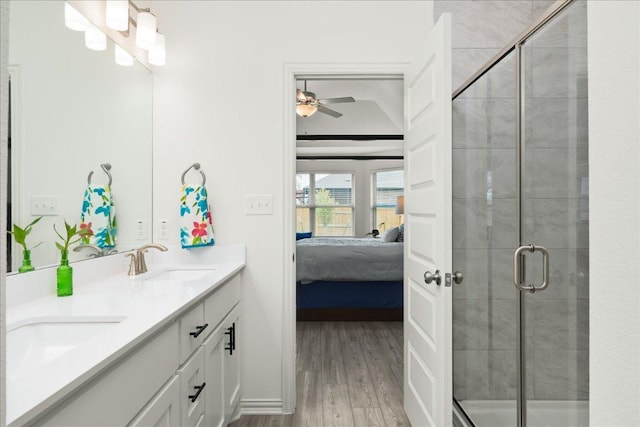 ensuite bathroom with a sink, wood finished floors, ensuite bath, a shower stall, and double vanity