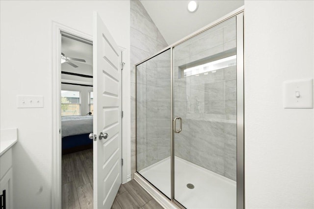 ensuite bathroom with wood finish floors, a stall shower, ensuite bath, vanity, and vaulted ceiling