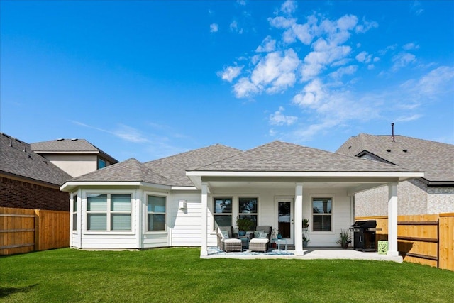 back of house with a patio area, a lawn, a fenced backyard, and a shingled roof