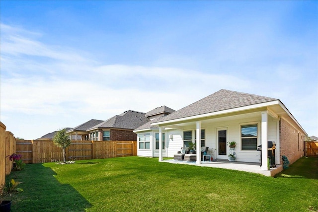 back of property with a patio, a yard, a fenced backyard, a shingled roof, and brick siding