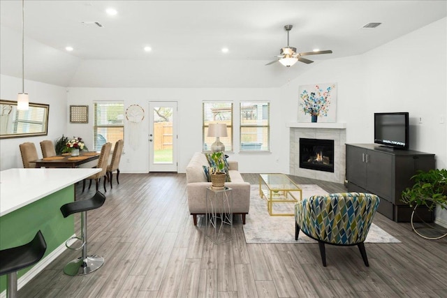 living room with visible vents, lofted ceiling, recessed lighting, a tile fireplace, and wood finished floors