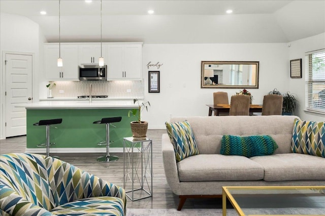 living room with recessed lighting, baseboards, lofted ceiling, and wood finished floors