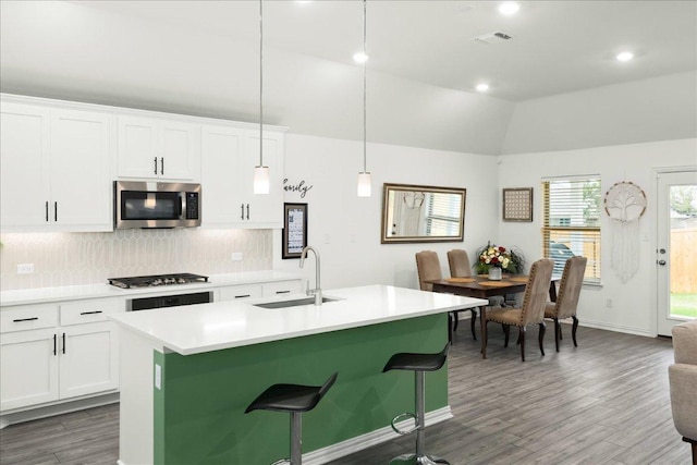 kitchen with an island with sink, a sink, stainless steel microwave, gas cooktop, and light wood finished floors