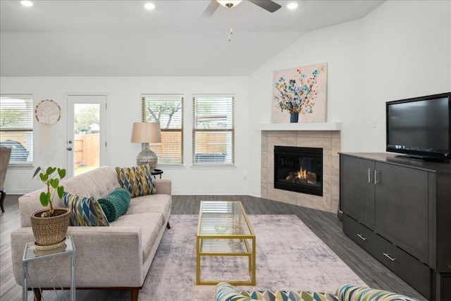 living area featuring lofted ceiling, a tiled fireplace, wood finished floors, recessed lighting, and baseboards