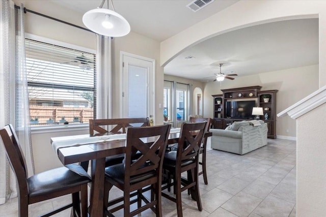 dining room featuring visible vents, arched walkways, light tile patterned floors, baseboards, and ceiling fan