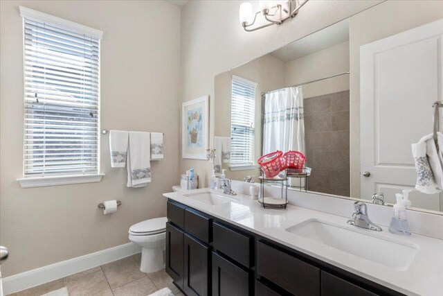 full bath with tile patterned flooring, toilet, baseboards, and a sink