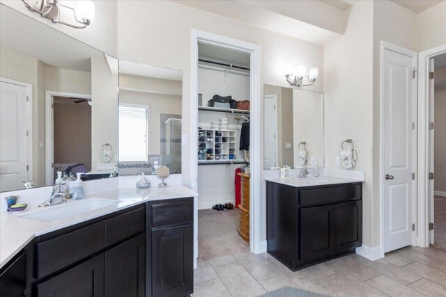 bathroom featuring tile patterned flooring, a shower stall, two vanities, and a sink