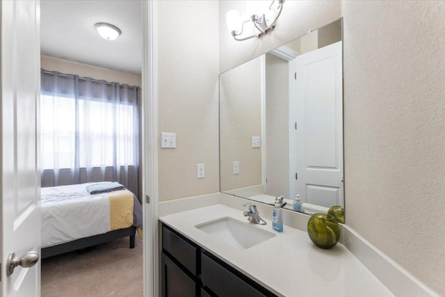 ensuite bathroom with connected bathroom, vanity, and a textured wall