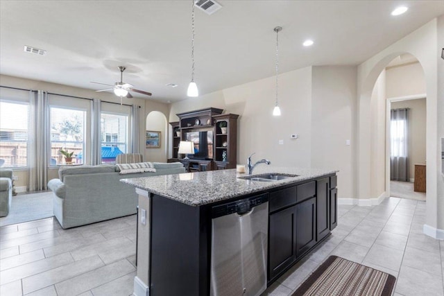 kitchen featuring visible vents, dishwasher, light stone counters, arched walkways, and a sink