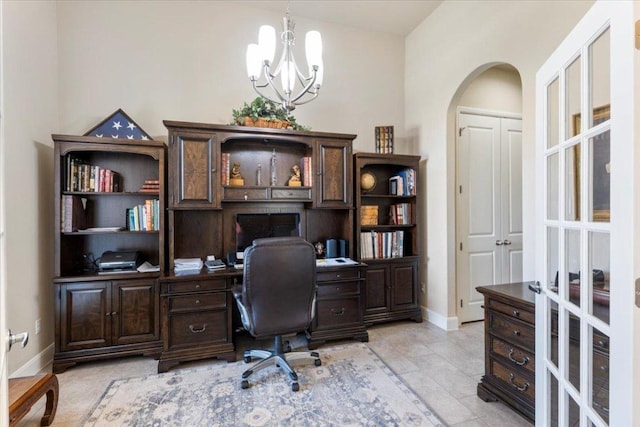 office area with arched walkways, a notable chandelier, baseboards, and light tile patterned flooring