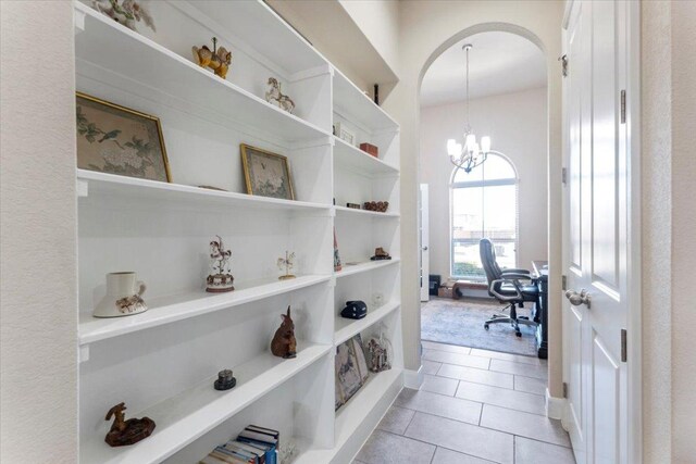 interior space featuring light tile patterned floors, arched walkways, and a chandelier