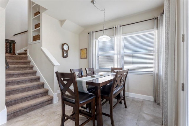 dining space featuring stairs, light tile patterned floors, and baseboards