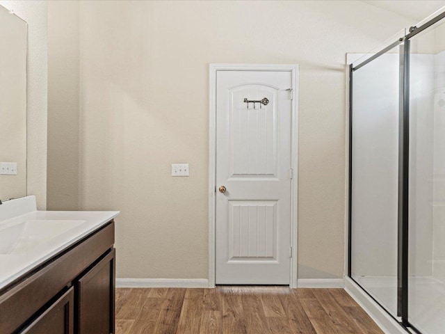 full bath featuring a stall shower, baseboards, wood finished floors, and vanity