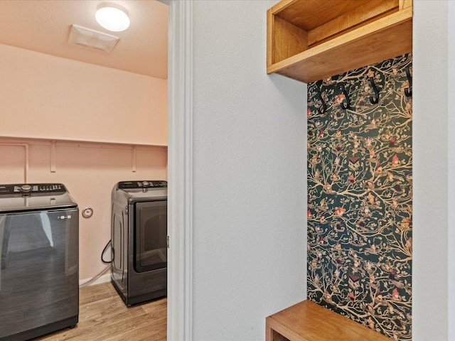 laundry area with laundry area, separate washer and dryer, visible vents, and light wood finished floors