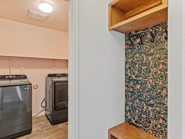 laundry area featuring visible vents, washer and clothes dryer, light wood-type flooring, and laundry area